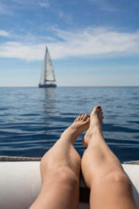point-of-view-shot on legs hanging over the edge of a dinghy on the sea point-of-view-shot on legs hanging over the edge of a dinghy on the sea